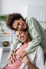 Happy african american woman holding hands of boyfriend at home.