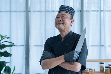 The Asian man with kitchen knife presenting a set of sashimi. Working hours in sushi bar. Happy proud Asian chef smiling.