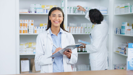 Obraz premium Portrait of a cheerful and friendly pharmacist using a digital tablet to check inventory or online orders in a chemist. Young latino woman using pharma app to do research on medication in a pharmacy