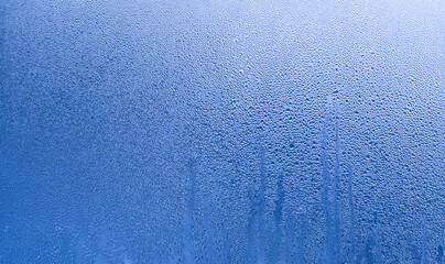 the gradient of the blue background of wet glass. Background condensation of water on the window glass due to high humidity.