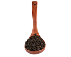 Wooden spoon with dry black tea leaves on a white background.