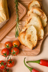 White toasted bread with rosemary hot peppers, cherry tomatoes on table.