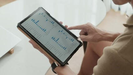 Hand of young male analyst scrolling through graphic financial data in tablet and studying charts illustrating market changes and development of new stock corporations - Powered by Adobe