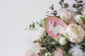 Banner. The concept of a bright Easter holiday. A bouquet of flowers with feathers and white rabbits on a white isolated background. Beautiful Easter card.