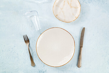 An empty plate with cutlery and a wineglass, place setting at a restaurant, dinner reception concept, overhead flat lay shot