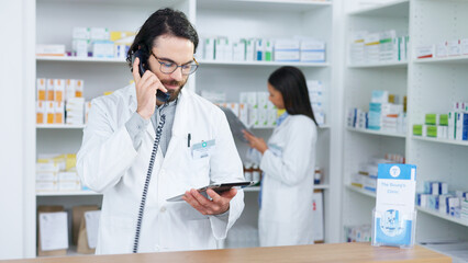 Pharmacist man answering the telephone and giving advice to customer on flu shot treatment options in pharmacy. Chemist assisting remote client by checking medicine stock on tablet