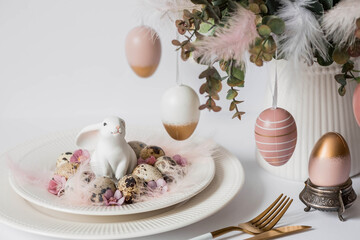 Banner. The concept of a bright Easter holiday. A bouquet of flowers with feathers, white rabbits and Easter eggs in a plate on a white isolated background. Beautiful Easter card.
