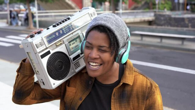 Young african female street musician rapping in the city while holding vintage boombox
