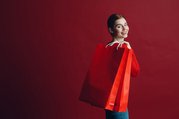 Fototapeta premium Pretty woman smilng portrait with paper red shopping bags. Black friday and sale concept