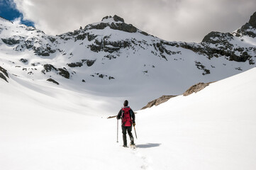 Fototapeta na wymiar Snow hiker walking in a snowy hillside in a cloudy day