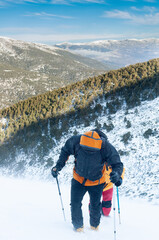 Two snow hikers climbing a snowy mountain during a snowstorm