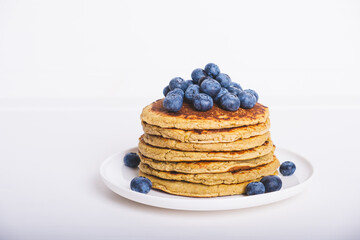 Delicious freshly cooked thick and fluffy gluten free pancakes stacked on white plate served with fresh blueberries. Copy space for text. Healthy food - obrazy, fototapety, plakaty