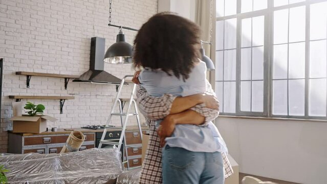 Happy loving husband lifts his wife, circles her, shares happiness, moving into new own apartment