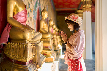 Naklejka premium thai woman praying and making wai at wat arun temple in bangkok thailand
