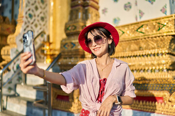 Obraz na płótnie Canvas happy thai woman taking seflie at wat arun temple in bangkok thailand