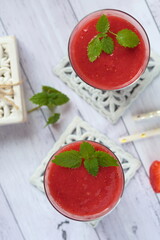 Strawberry smoothie garnished with fres mint leaves.
