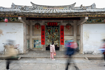 Moving crowd in front of a Chinese historical house. The text on the house means "Inheriting the past".