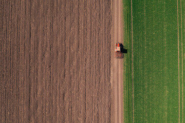 Aerial view of agricultural tractor with tiller attached driving on dirt road