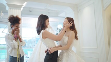 Naklejka premium Asian beautiful bridesmaids congratulate your friend on becoming a bride chossing the white wedding dress for wedding ceremony at wedding studio