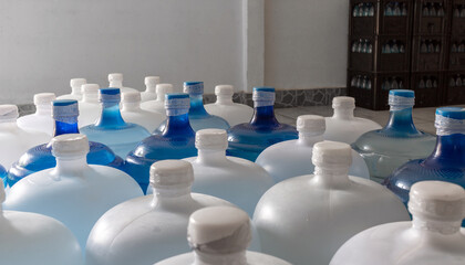 Plastic big bottles or white and blue gallons of purified drinking water inside the production line. Water drink factory