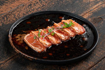 Fresh salmon fillet cut into pieces on a plate with soy sauce. Asian dish sashimi from raw salmon