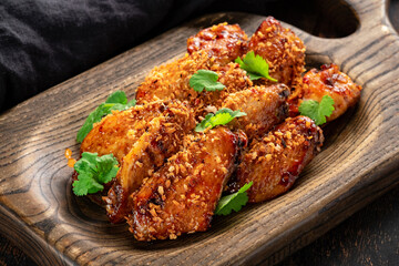 Pieces of fried chicken meat in barbecue sauce with parsley and crackers on a wooden board. Chicken Wings BBQ dish