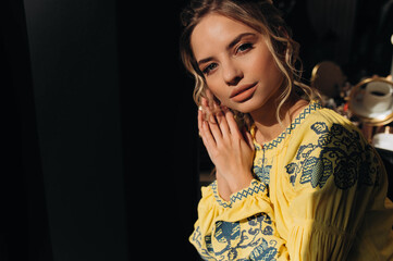 A young Ukrainian woman is sitting in a room in traditional national clothes. Ethnic Ukrainian national clothing style.