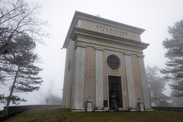 Fototapeta na wymiar Chapel of the appearace near the Sanctuary of Our Lady of the Guard (Madonna della Guardia) in the fog, in winter time, in Genoa, Italy.