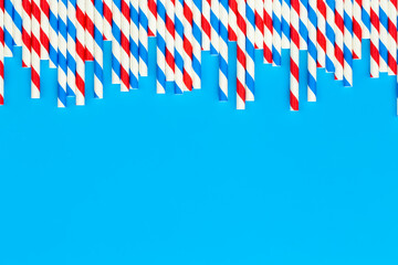 Obraz premium Drinking straws for party on blue background with copy space.