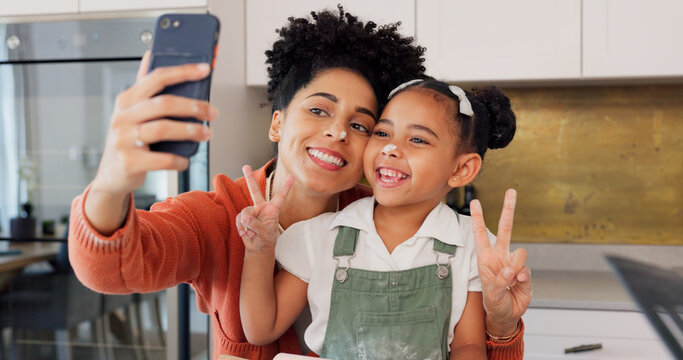 Mother, girl and phone selfie while cooking in kitchen, bonding and having fun. Learning, baking and mom, kid and 5g mobile for social media, picture or online post with victory hands or peace sign