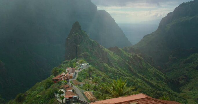 Sunlight through fog and rain in mounatains rural landscape with small village buildings in Masca valley Tenerife.
