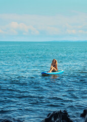 SUP Stand up paddle board. Romantic girl on paddle board in the sea near stone beach. Summer holidays vacation travel. Mtsvane Kontskhi Beach, Batumi, Georgia.