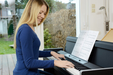Pretty blonde woman as a pianist plays music on piano 