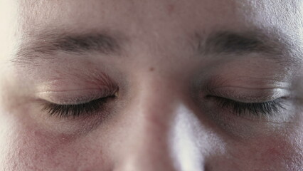Obraz premium Person closing eyes in meditation and opening looking at camera. Macro close up of calm man eye in contemplation