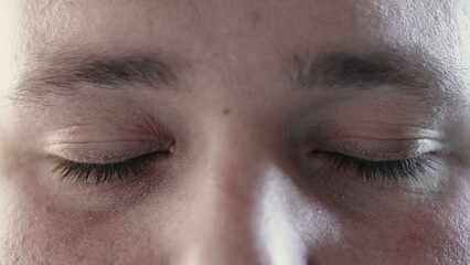 Naklejka premium Person closing eyes in meditation and opening looking at camera. Macro close up of calm man eye in contemplation