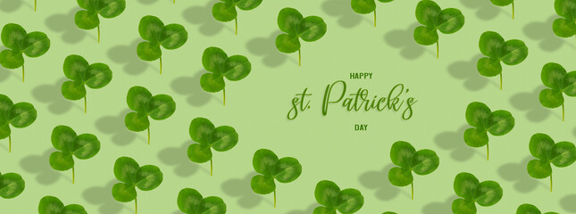 Happy St. Patrick's Day text with clover leaf pattern on colored background. Greeting banner