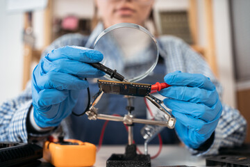 Young woman repairing computer in a repair shop. She uses different tools. Computer repair specialist.