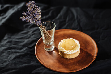 Lemon tartlet on a dark background. Fashionable European dessert with fruit filling.