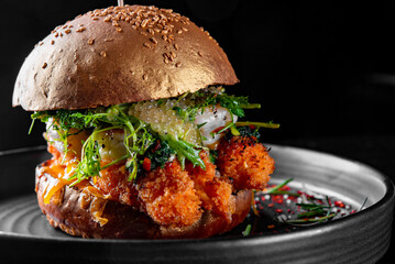 Delicious seafood burger with shrimps, crab, caviar, cheese and vegetables on a black background