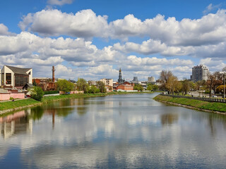 Fototapeta premium Cityscape Kharkiv city and Lopan river embankment on a sunny spring day. Cumulus clouds on blue sky