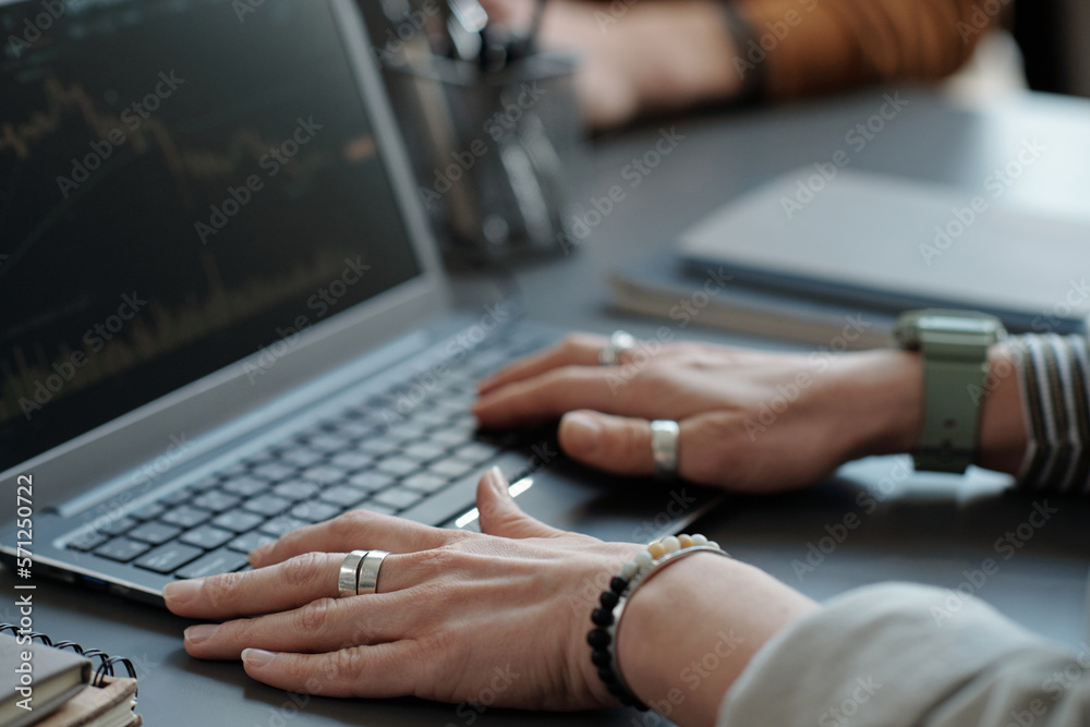Aufkleber Hands of female trader or broker touching laptop keyboard while sitting by workplace in office, analyzing financial data and creating graph
