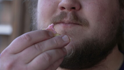 Fototapeta premium One fat guy eating last piece of doughnut donut. Closeup mouth chewing junk food