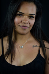 Portrait of a serene and positive young Brazilian woman in a black top, against a dark background