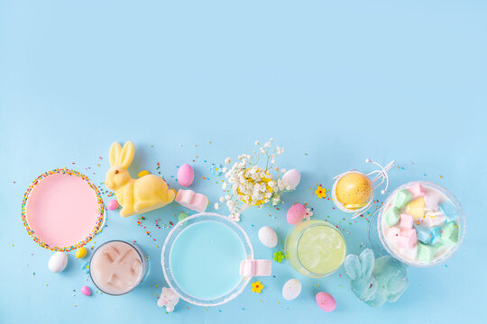 Colorful Pastel Colored Kids Easter Party Mocktails, Creamy And Iced Non-alcohol Drinks With Cotton Candy, Marshmallow, Sugar Sprinkles And Easter Eggs, On Blue Pink Pastel Background Copy Space