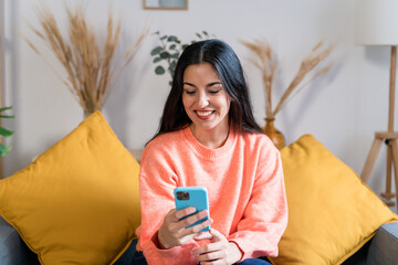 Cheerful woman using smartphone on sofa