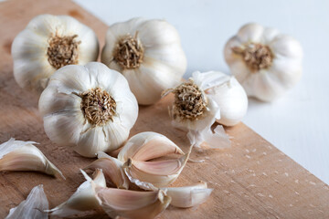 garlic bulbs with garlic cloves on a wooden cutting board.