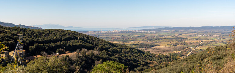 Obraz premium Italy Grosseto Maremma, route in MTB and EMTB in the woods of Gavorrano up to Mount Calvo, panoramic view of the village and the valley to the sea, Elba Island in the background