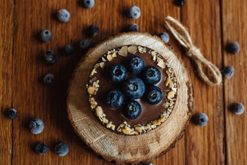 Delicious tartlet with fresh blueberries and chocolate, on wooden background. Trendy dessert. Top view