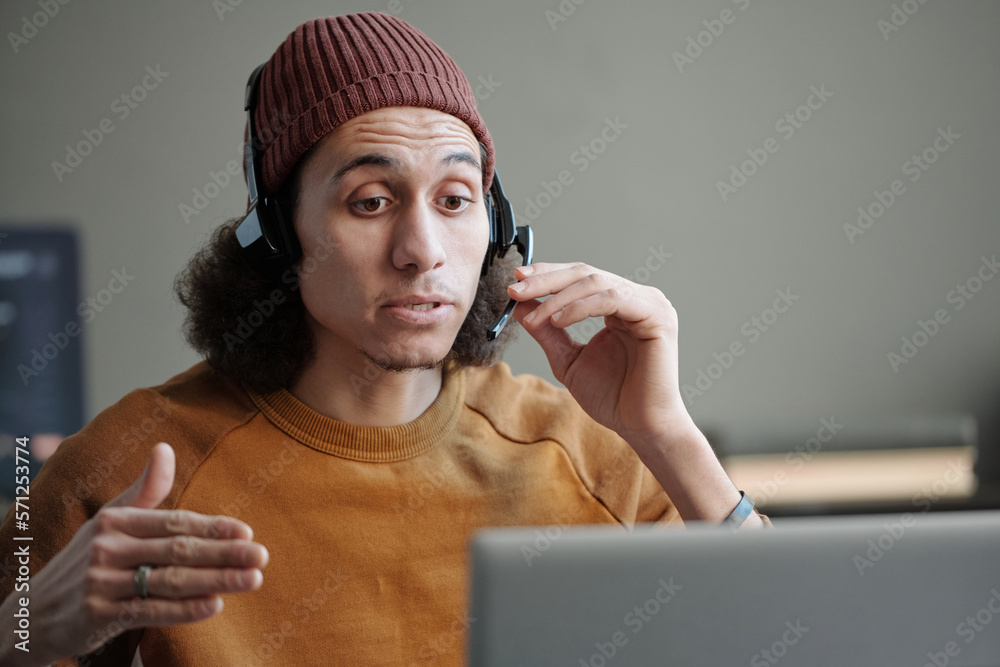 Aufkleber young confident it support manager or helpdesk operator in headset looking at laptop screen and cons