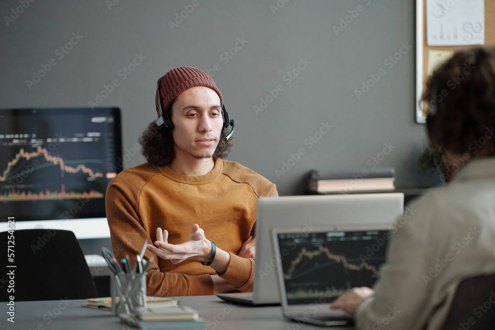 Aufkleber confident young helpdesk operator in casualwear sitting by workplace in front of laptop and explaini